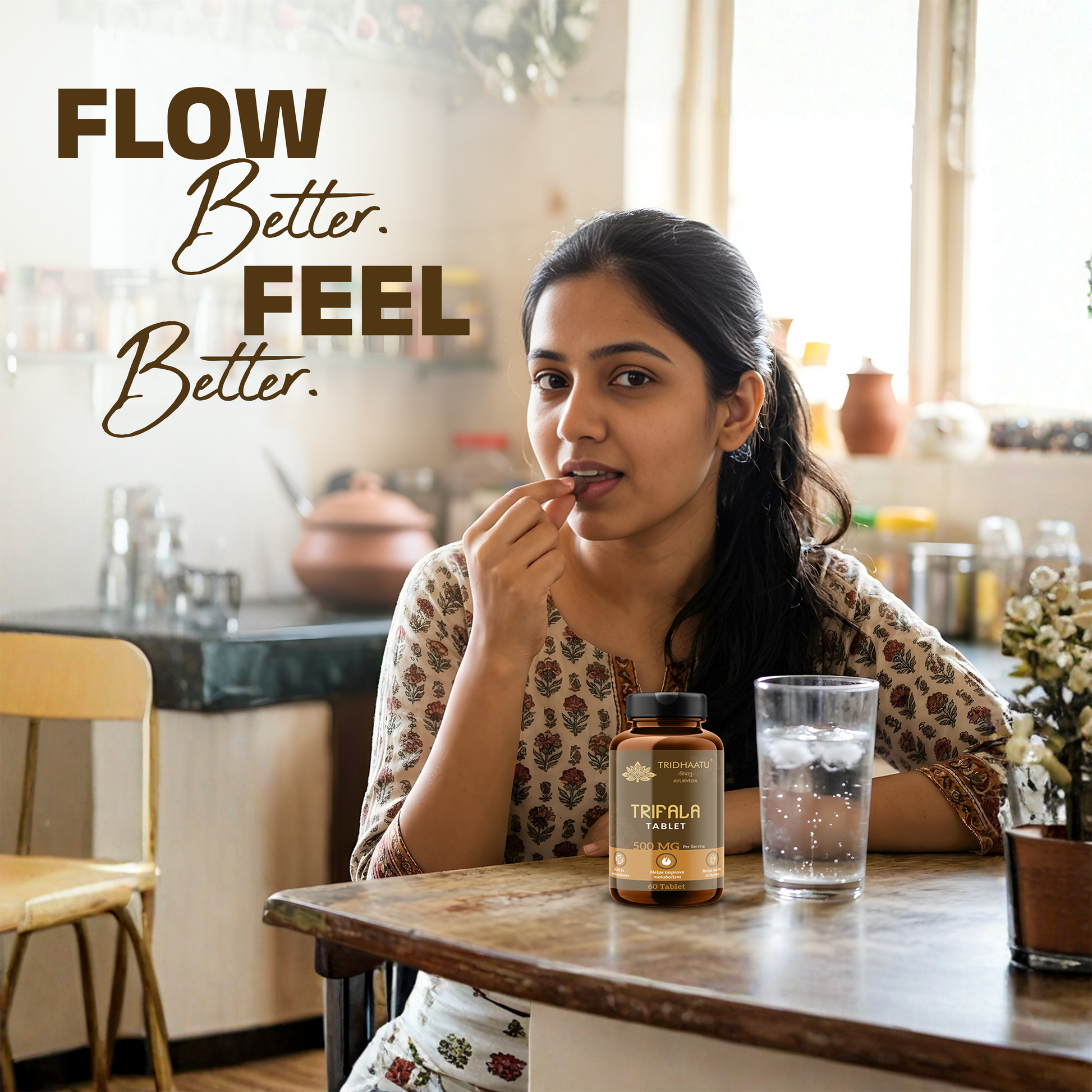 Woman sitting at a table with a bottle of Triphala tablets and a glass of water, with text 'Flow Better. Feel Better.'